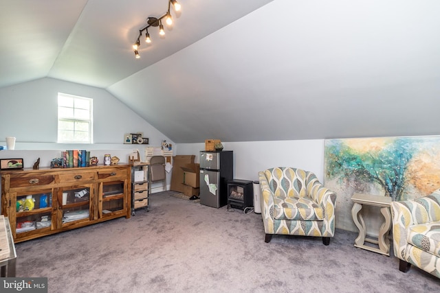 interior space with a wood stove, carpet, and vaulted ceiling