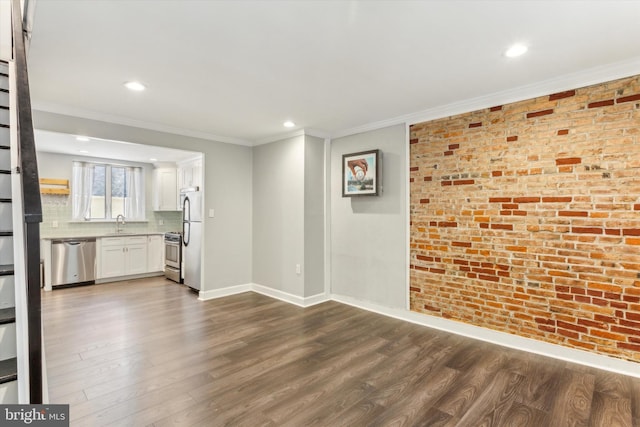 unfurnished living room featuring sink, ornamental molding, dark wood-type flooring, and brick wall