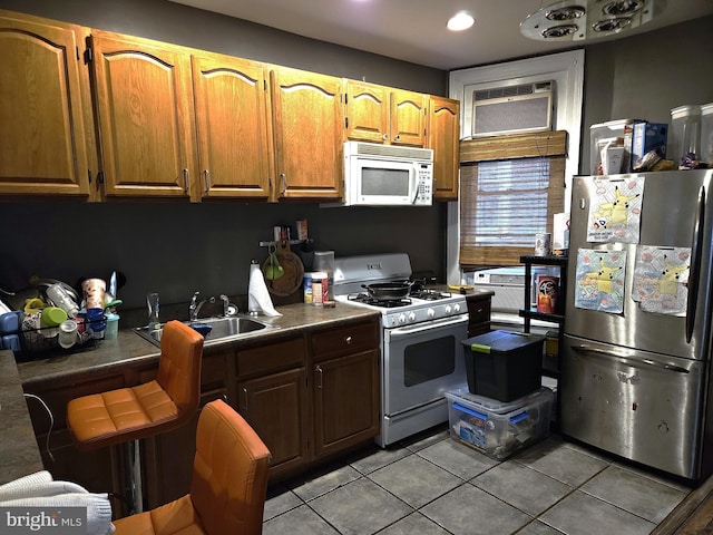 kitchen featuring white appliances, sink, light tile patterned floors, and a wall mounted AC