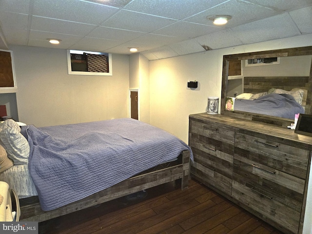 bedroom with a paneled ceiling and dark wood-type flooring