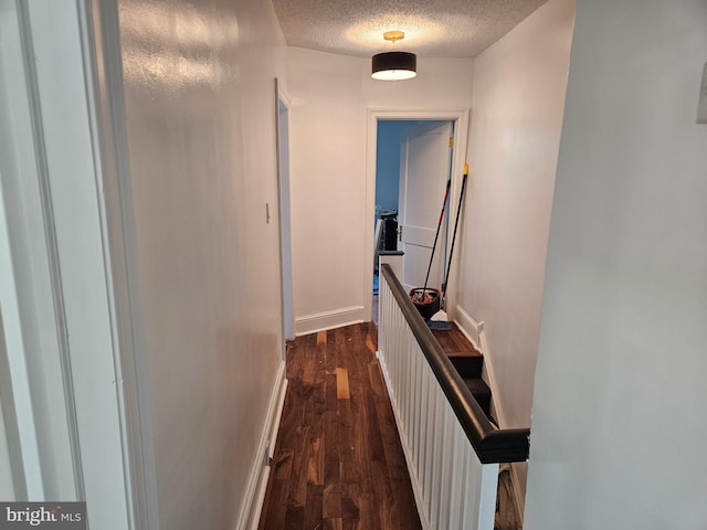 hallway featuring a textured ceiling and dark hardwood / wood-style floors