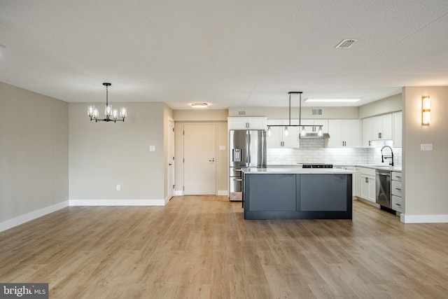 kitchen featuring pendant lighting, white cabinets, sink, light hardwood / wood-style floors, and stainless steel appliances