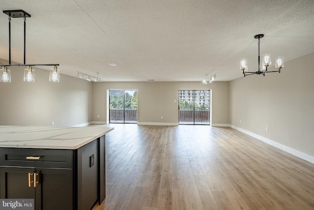 interior space with a notable chandelier, a textured ceiling, and light wood-type flooring