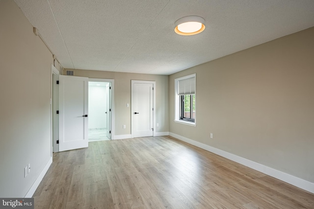 unfurnished bedroom featuring light wood-type flooring and a textured ceiling