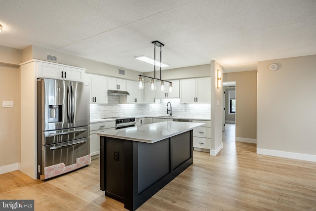 kitchen featuring white cabinets, decorative light fixtures, a center island, and stainless steel appliances