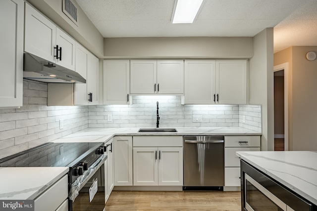 kitchen with white cabinets, appliances with stainless steel finishes, light hardwood / wood-style flooring, and sink