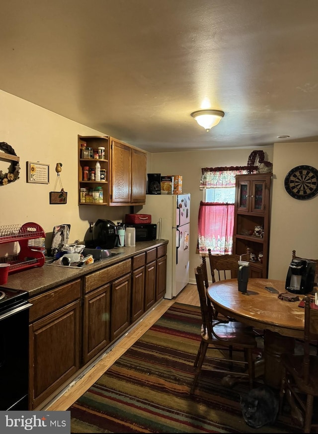 kitchen featuring electric range, dark brown cabinets, white fridge, and wood-type flooring