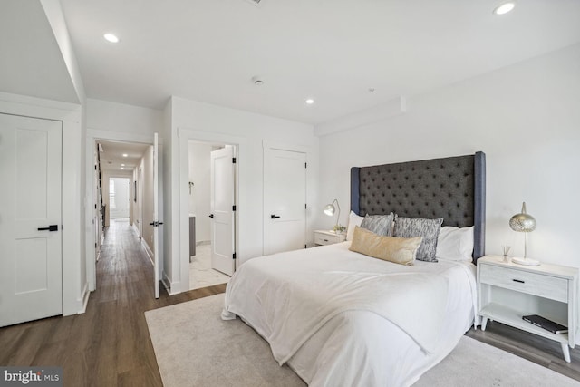 bedroom featuring ensuite bath and dark hardwood / wood-style flooring