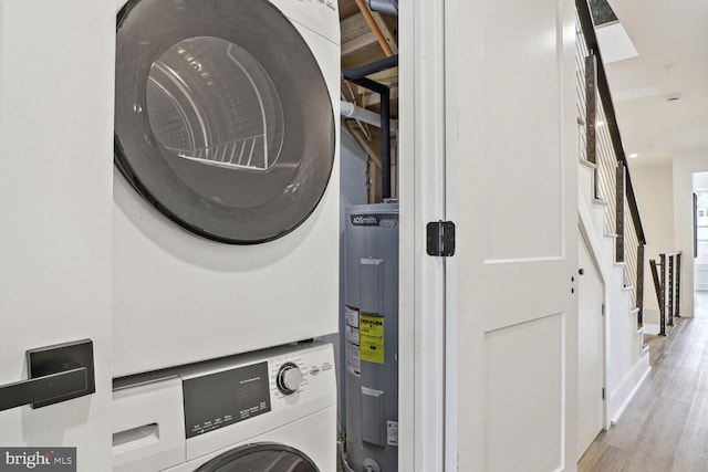 washroom featuring electric water heater, stacked washer and clothes dryer, and hardwood / wood-style flooring