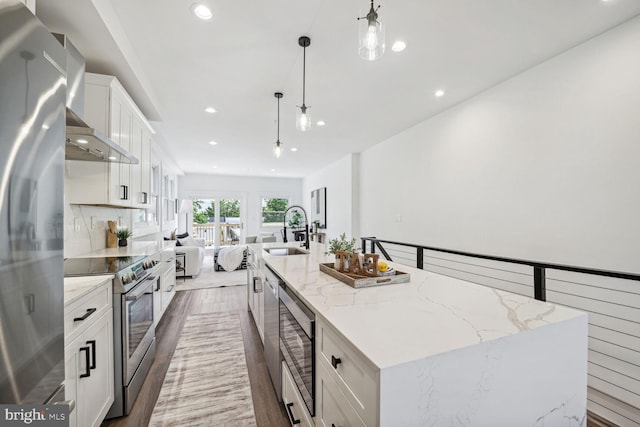 kitchen featuring stainless steel appliances, hardwood / wood-style floors, and a center island with sink