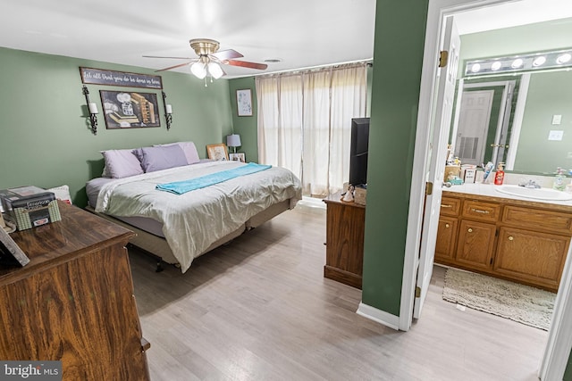 bedroom with light hardwood / wood-style floors, ensuite bath, ceiling fan, and sink