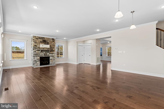 unfurnished living room with dark hardwood / wood-style flooring, a stone fireplace, and crown molding