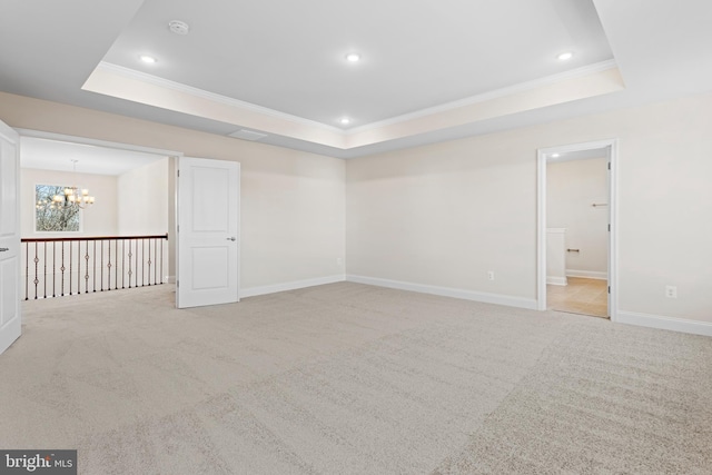 carpeted empty room featuring a tray ceiling, ornamental molding, and an inviting chandelier