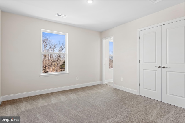 unfurnished bedroom featuring light colored carpet and a closet