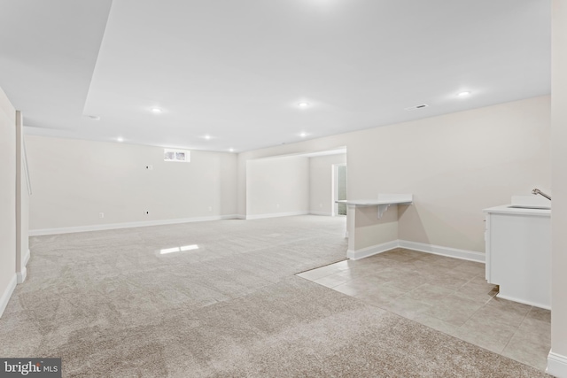 basement featuring light colored carpet and sink