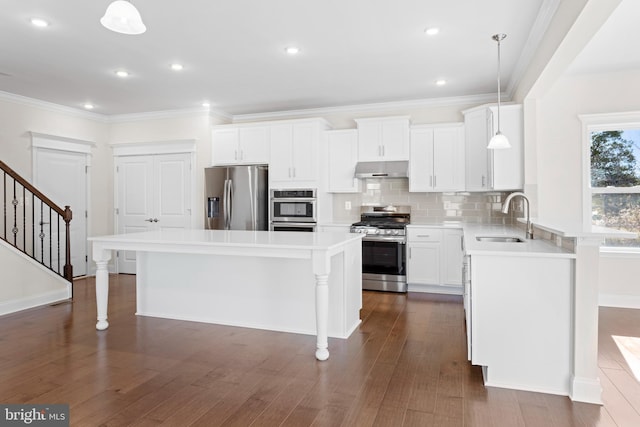 kitchen with dark wood-type flooring, pendant lighting, a kitchen island, and stainless steel appliances