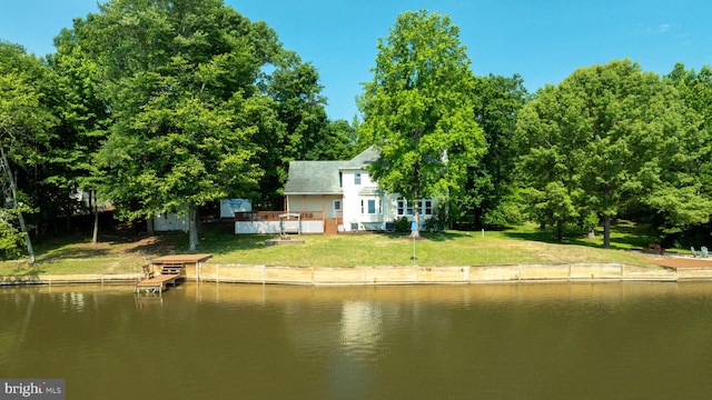 back of house with a lawn and a deck with water view