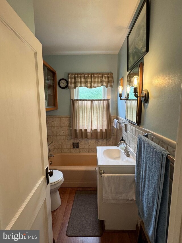 bathroom featuring a tub, vanity, wood-type flooring, and toilet