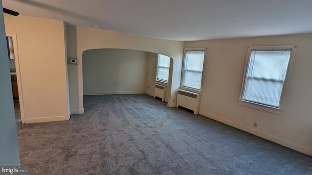 carpeted empty room featuring radiator heating unit and plenty of natural light