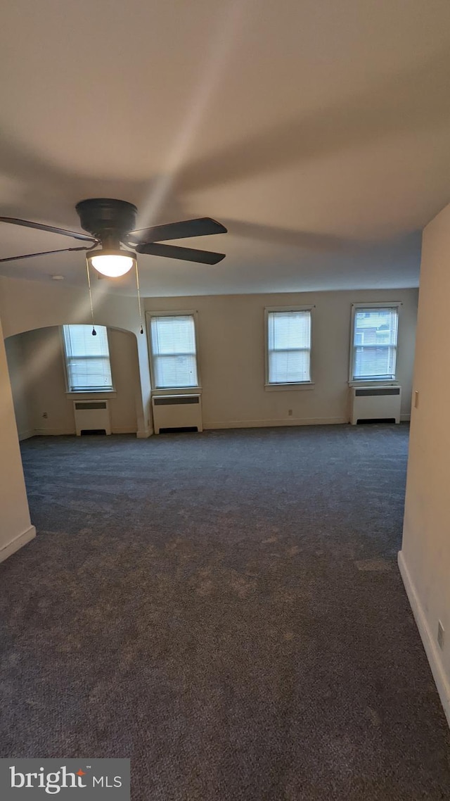 unfurnished room with ceiling fan and dark colored carpet