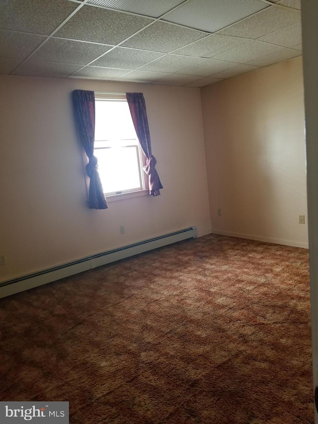 carpeted spare room with a paneled ceiling and a baseboard heating unit