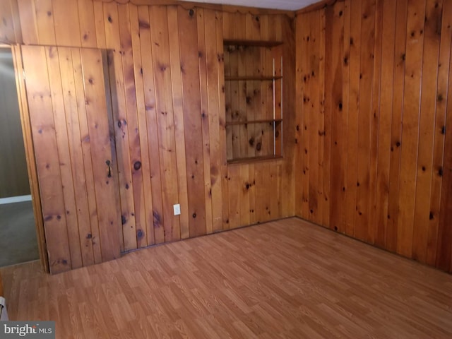 empty room featuring wood walls and light hardwood / wood-style floors