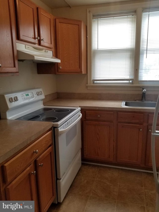 kitchen featuring dark tile patterned flooring, white electric range oven, plenty of natural light, and sink