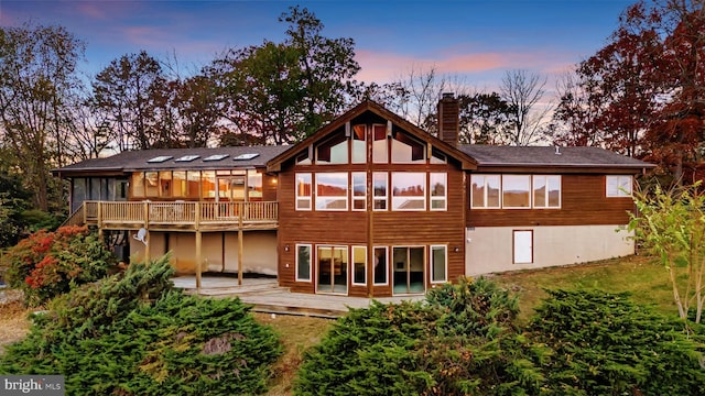 back house at dusk featuring a deck