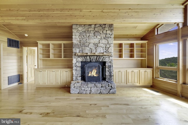 unfurnished living room with wood walls, lofted ceiling, wooden ceiling, a fireplace, and light hardwood / wood-style floors