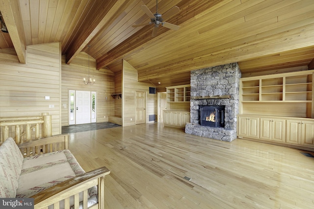 unfurnished living room featuring wood ceiling, lofted ceiling with beams, light hardwood / wood-style flooring, a stone fireplace, and wood walls