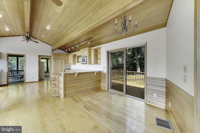 kitchen with a kitchen breakfast bar, ceiling fan with notable chandelier, light hardwood / wood-style flooring, vaulted ceiling with beams, and kitchen peninsula