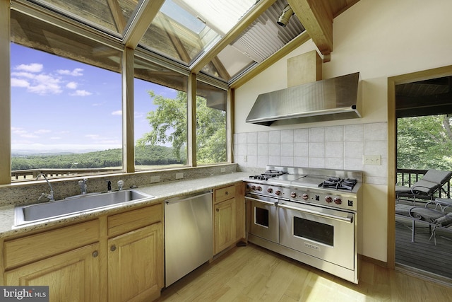 kitchen featuring sink, wall chimney exhaust hood, light hardwood / wood-style floors, light brown cabinetry, and appliances with stainless steel finishes