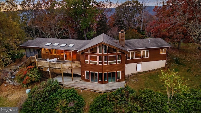 back house at dusk with a wooden deck