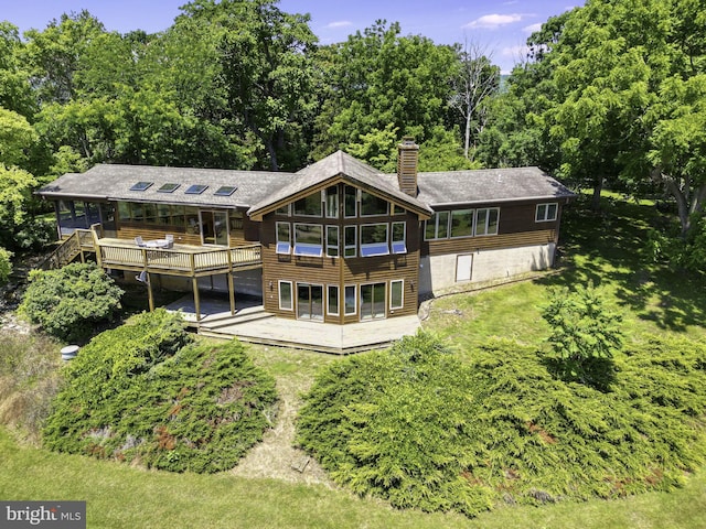 rear view of house featuring a lawn and a wooden deck