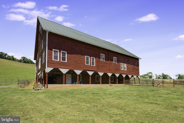 rear view of house featuring a rural view and a lawn