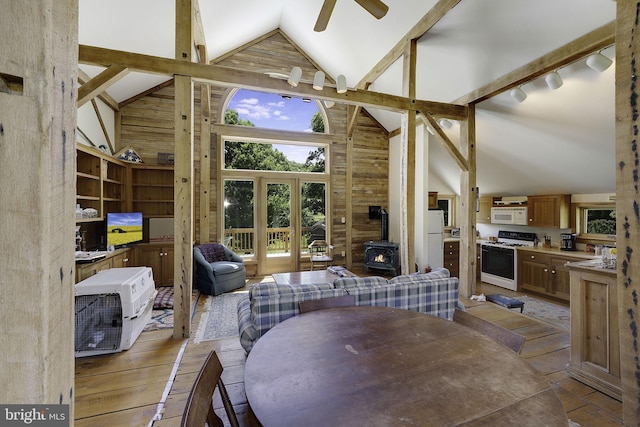 dining area with a wood stove, high vaulted ceiling, french doors, ceiling fan, and beamed ceiling