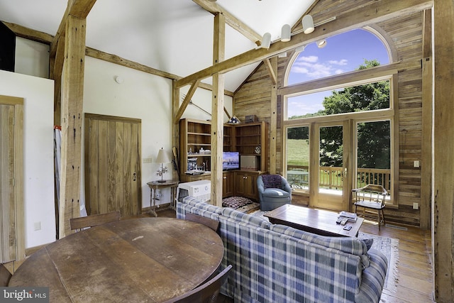 living room featuring hardwood / wood-style flooring, a wealth of natural light, wood walls, and high vaulted ceiling