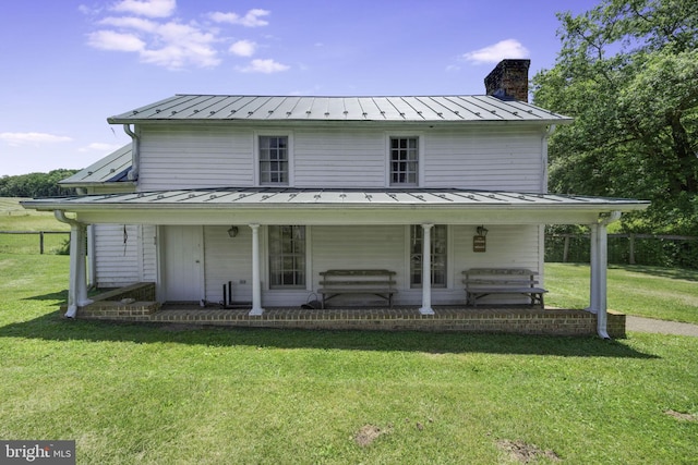 back of house with covered porch and a yard