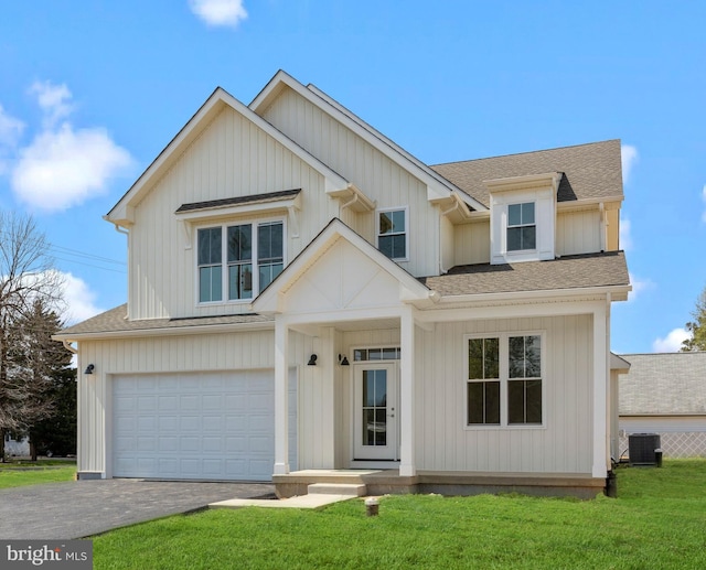 view of front of house with a garage, a front yard, and central AC