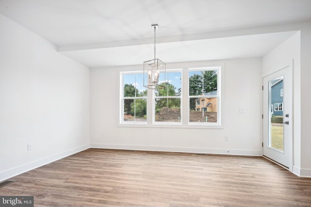 unfurnished dining area featuring hardwood / wood-style flooring, plenty of natural light, and a notable chandelier