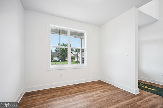 spare room with dark wood-type flooring and a wealth of natural light