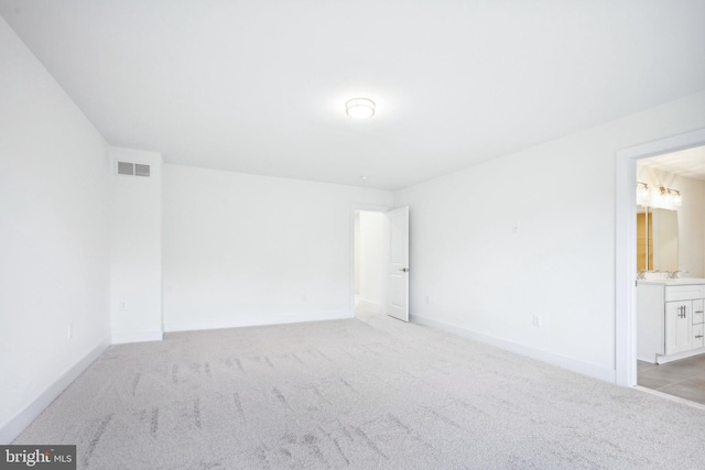empty room featuring a sink, visible vents, baseboards, and light colored carpet