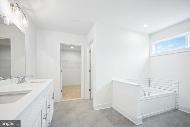 bathroom with a spacious closet, a bath, and a sink
