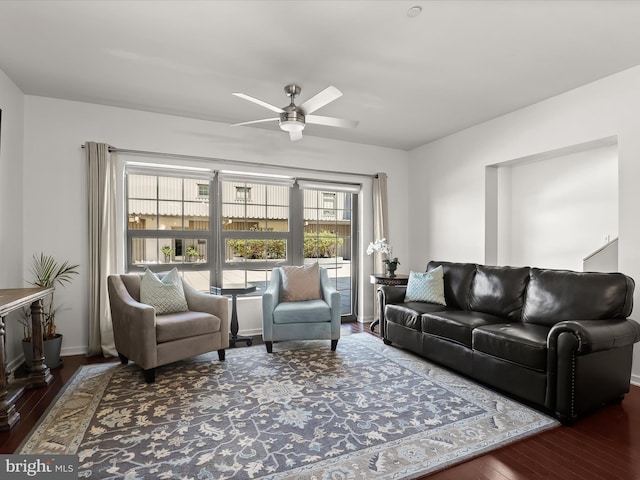 living area with baseboards, ceiling fan, and wood finished floors