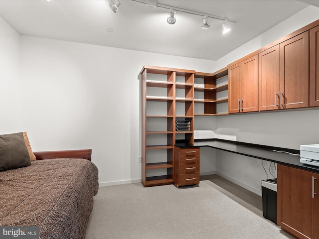 bedroom featuring built in desk, light colored carpet, and baseboards