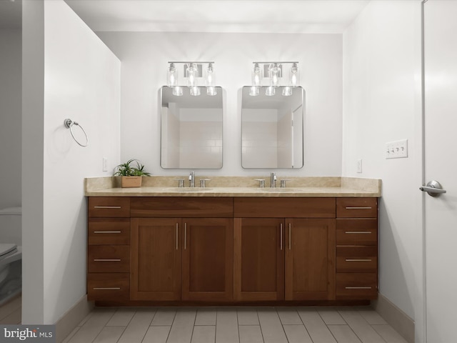 bathroom with a sink, baseboards, toilet, and double vanity