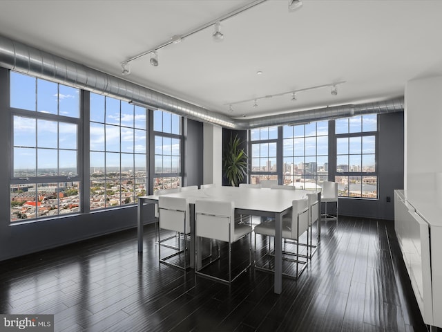 dining area with dark wood-style floors, track lighting, and a view of city