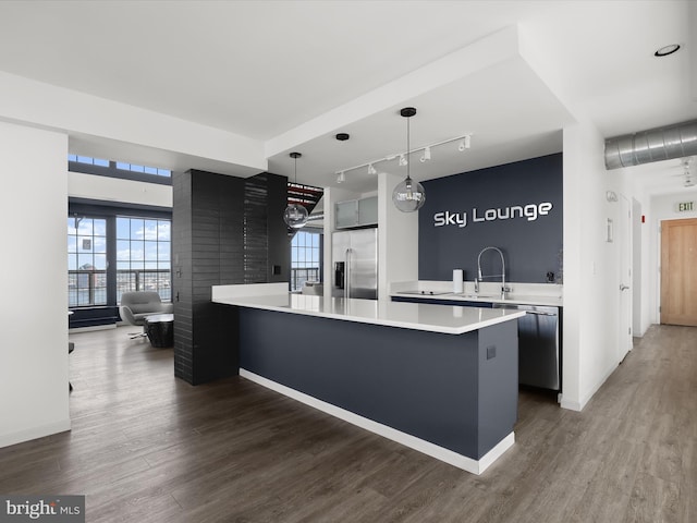 kitchen featuring appliances with stainless steel finishes, a peninsula, dark wood finished floors, and light countertops