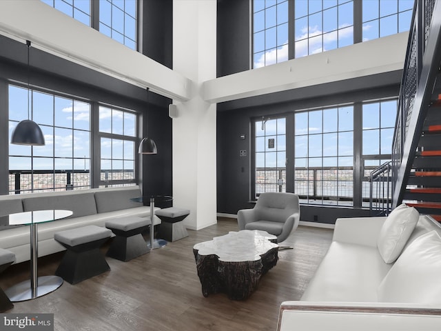 living room featuring baseboards, stairs, a towering ceiling, and wood finished floors