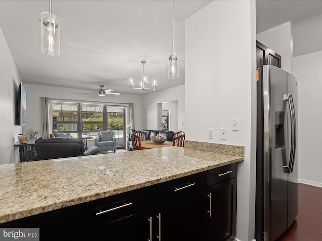 kitchen with light stone countertops, dark wood finished floors, open floor plan, stainless steel refrigerator with ice dispenser, and hanging light fixtures